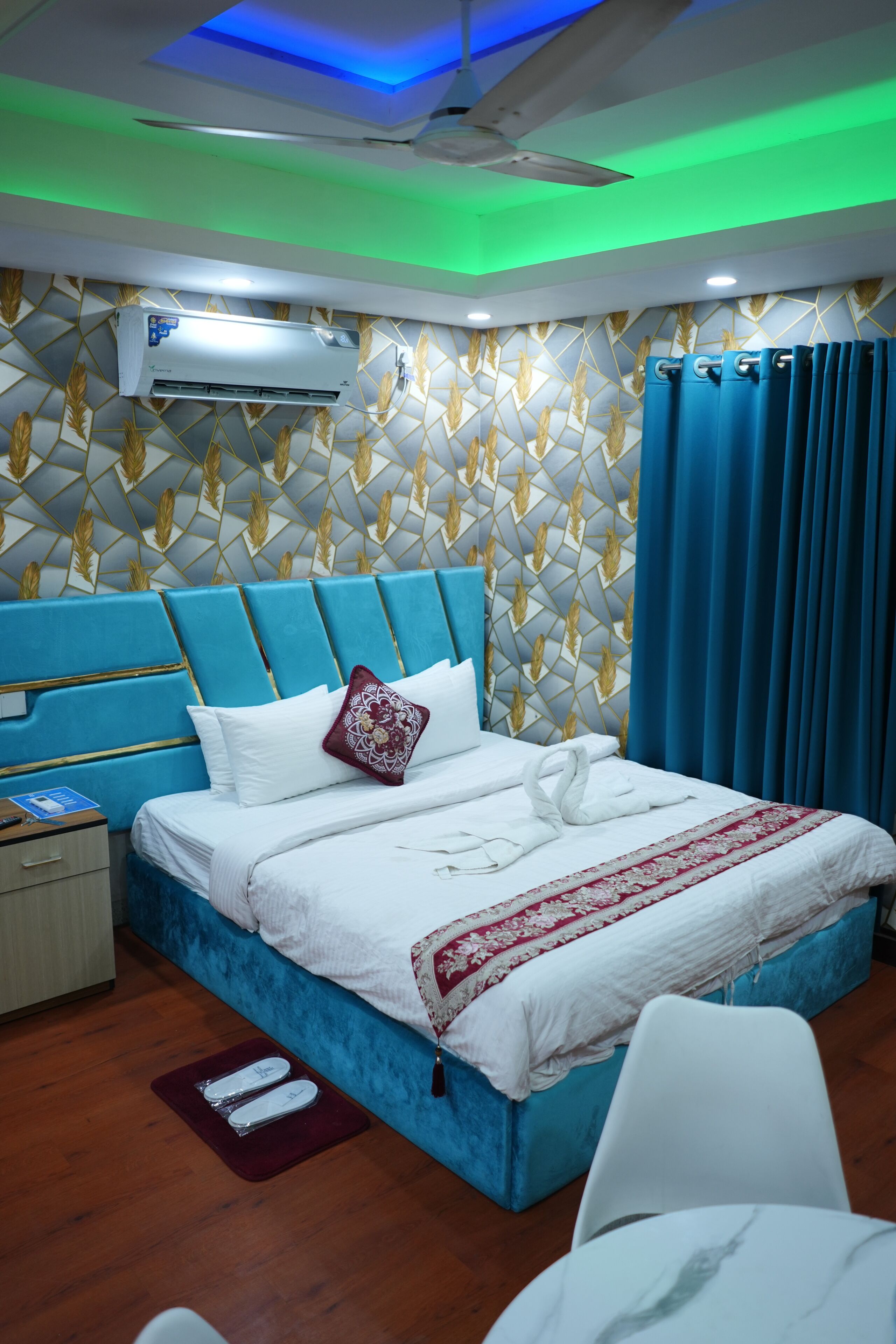 A modern bedroom with a blue headboard, white bedding, and a decorative wall pattern.