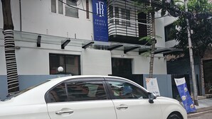 A white car parked in front of a building with a sign that reads "HOTEL FAMILY". - Hotel Family Inn (Dhaka)