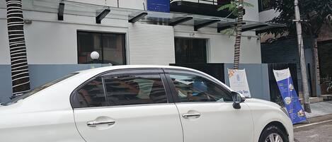 A white car parked in front of a building with a sign that reads "HOTEL FAMILY".