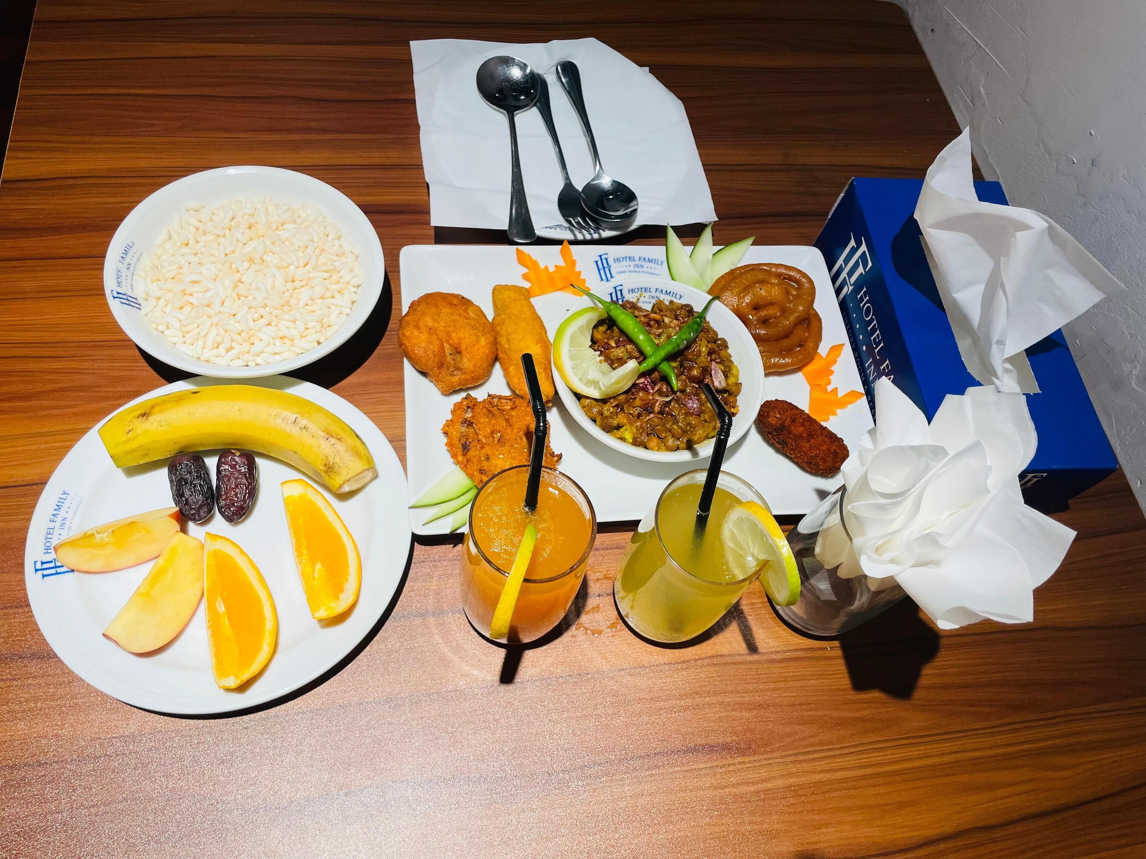 A table with plates of food, including rice, fried items, and a bowl of curry, along with two drinks and a banana.
