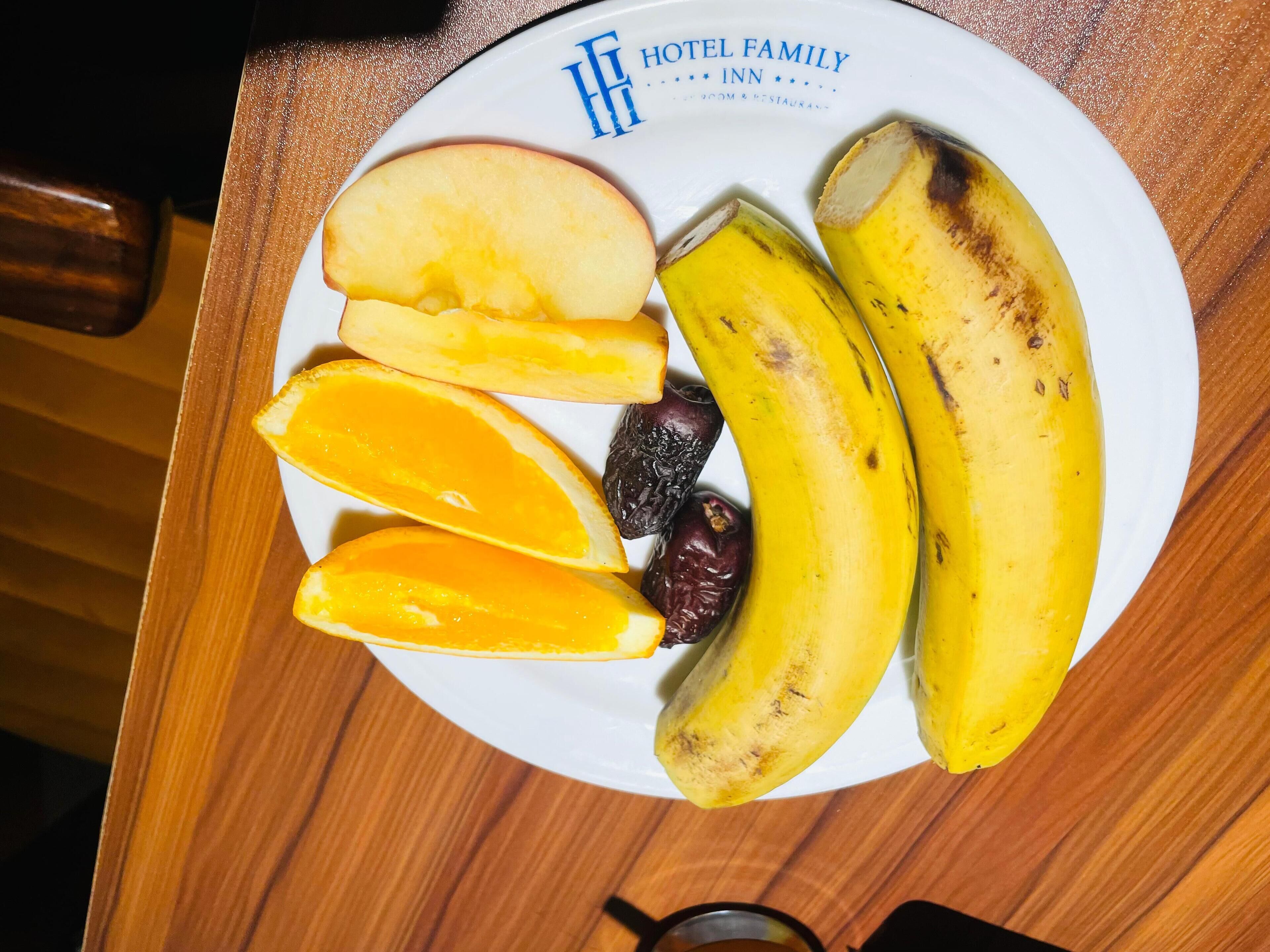 Un plato con frutas cortadas, como plátanos, manzanas y naranjas, sobre una mesa de madera.