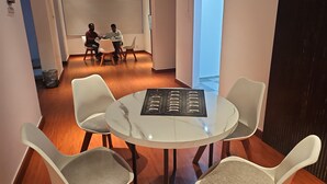A conference room with a white table and chairs, a menu on the table, and a view of a balcony through a large window. - Hotel Family Inn (Dhaka)