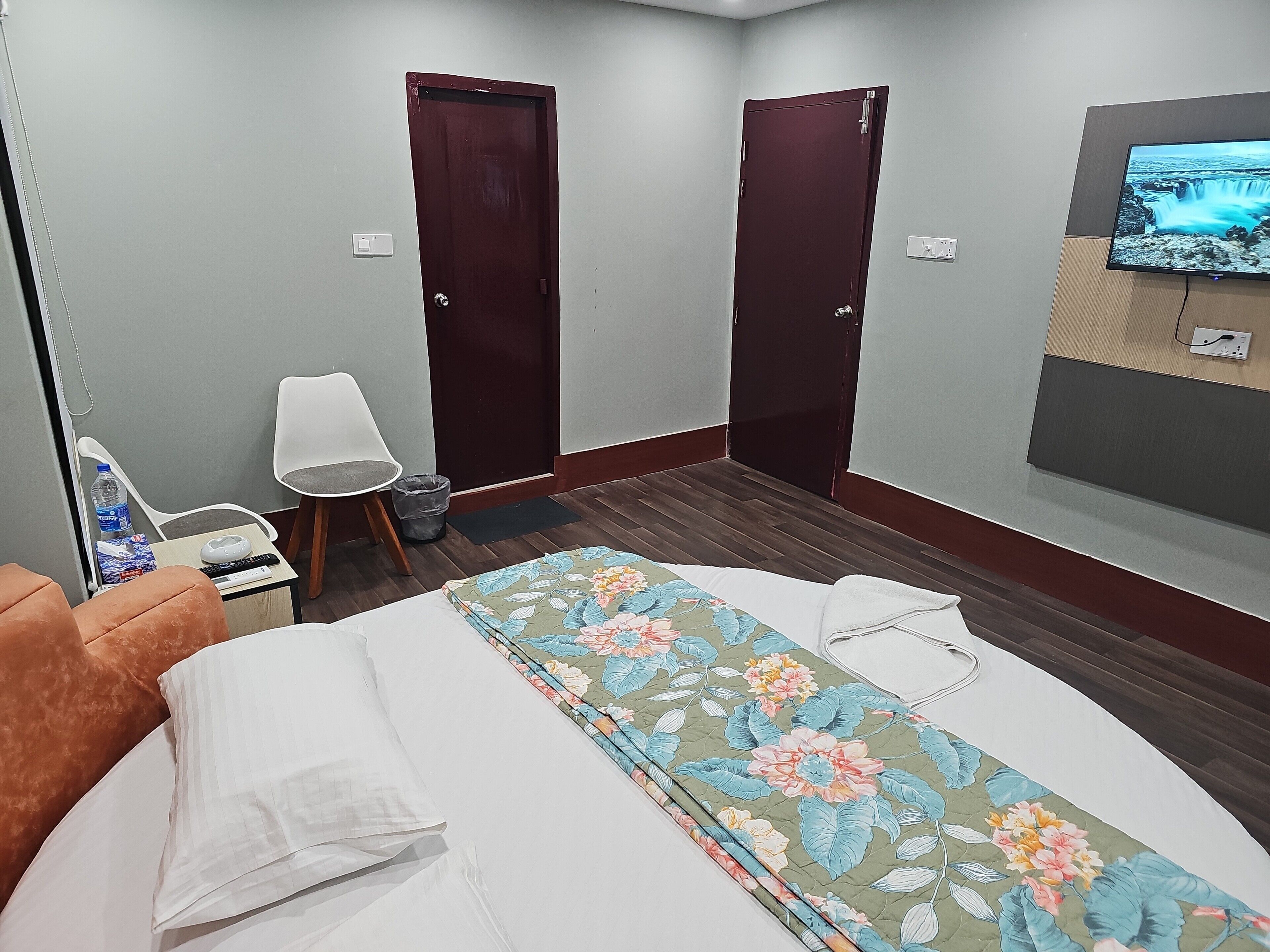 Une chambre d’hôtel avec un lit, une chaise, une télévision et deux portes.