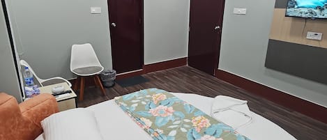 Une chambre d’hôtel avec un lit, une chaise, une télévision et deux portes.