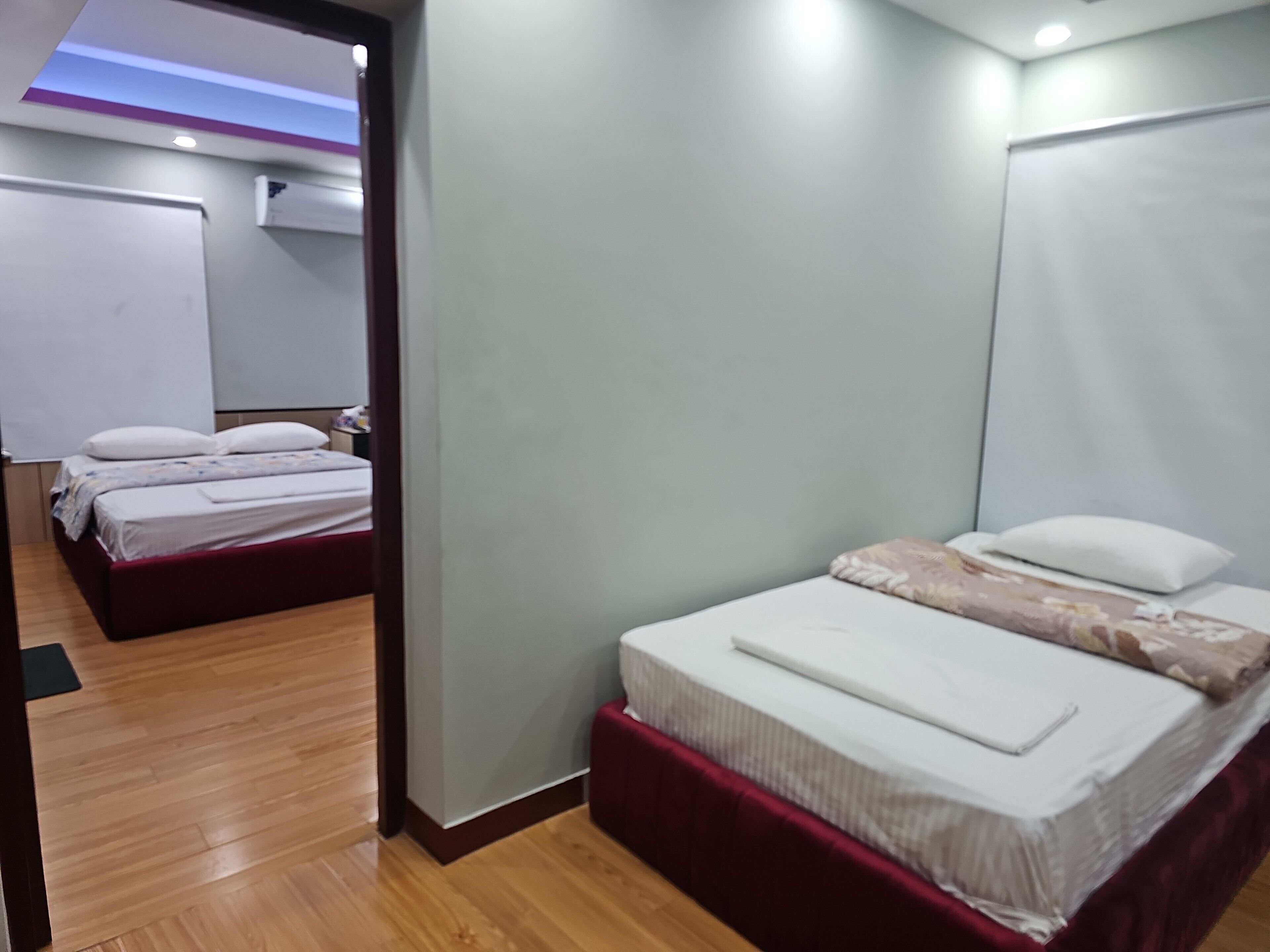 Ein Hotelzimmer mit zwei Betten, Holzboden und einer weißen Wand.
