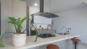 A modern kitchen with a central island, bar stools, and potted plants. - Penthouse de lujo (Barranquilla)