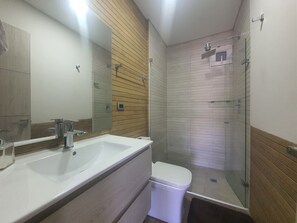 Ein modernes Badezimmer mit großem Spiegel, Waschbecken, Toilette und einer Duschkabine.