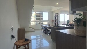 A modern kitchen with a central island, a dining area with a bench, and a staircase leading to an upper level. - Penthouse de lujo (Barranquilla)