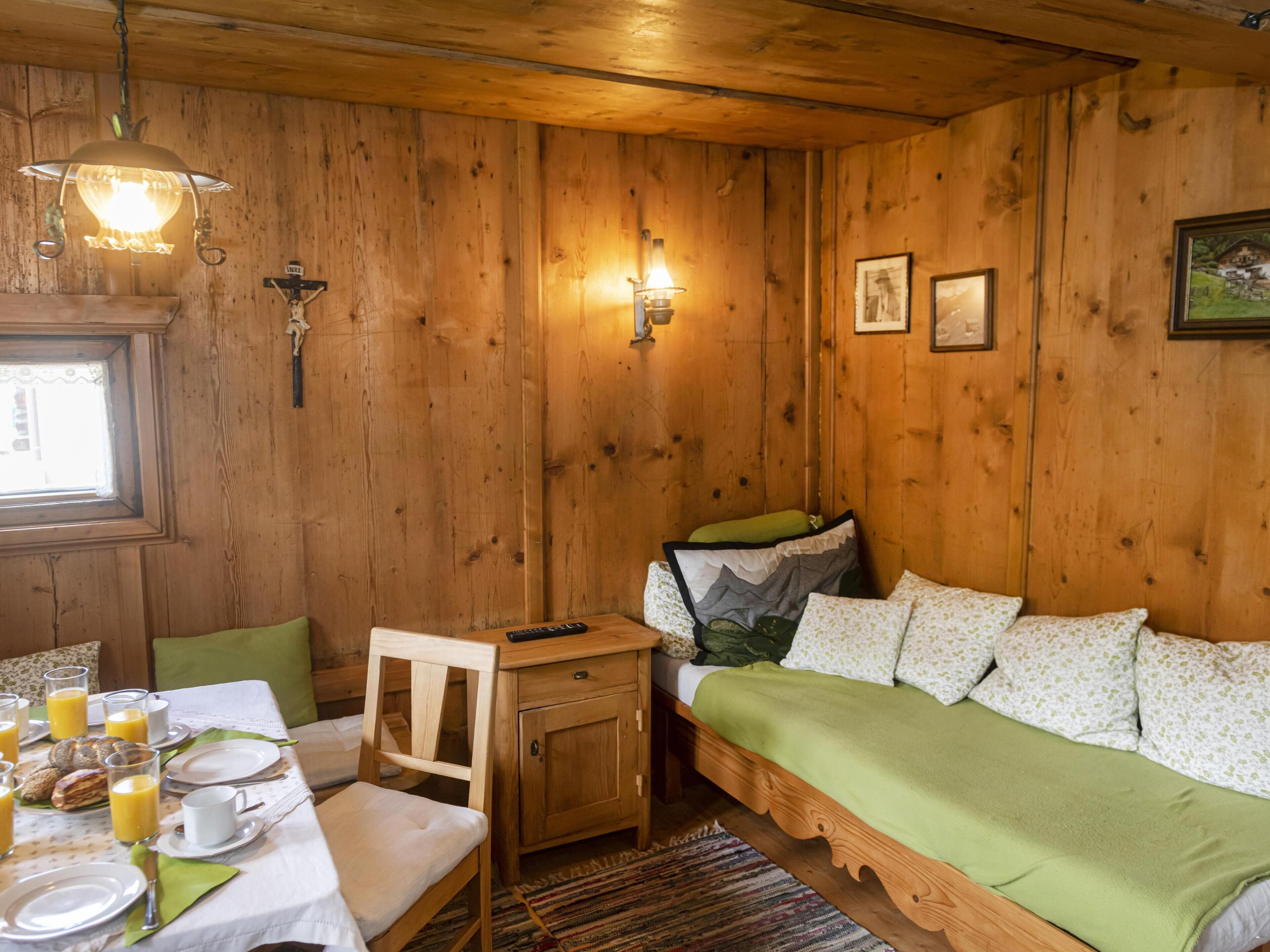 Una habitación acogedora de madera con una cama, una mesa lista para el desayuno y una ventana.