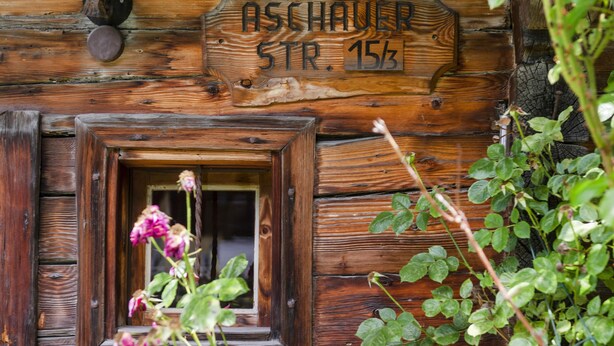 Un edificio rústico de madera con un cartel que dice "Aschauer Str. 15/3".
