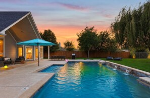 Un jardin avec une piscine, des meubles de jardin et une clôture en bois.