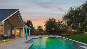 A backyard with a swimming pool, a covered patio, and a wooden fence. - The Perfect Getaway 5BR/4BA with Pool & Hot Tub (Ponder)