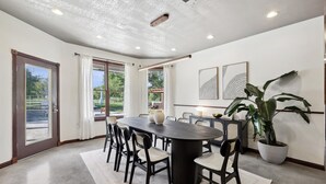 A dining area with a large round table, chairs, and a potted plant. - The Perfect Getaway 5BR/4BA with Pool & Hot Tub (Ponder)