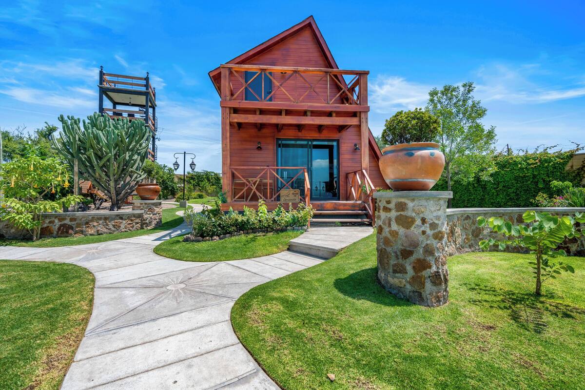 Una casa moderna con fachada de madera, base de piedra y un jardín cuidado.