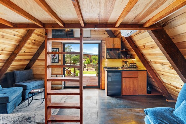 A cozy attic bedroom with a wooden ceiling, a built-in desk, and a view of the outdoors. - Xidó San Miguel (San Miguel de Allende)