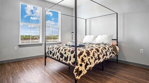 A four-poster canopy bed with a cowhide cover, two windows with blinds, and a view of a field. - Cozy 1-been apartment w/ WiFi, AC in fabulous North Fort Worth minutes 2 Dallas (Fort Worth)