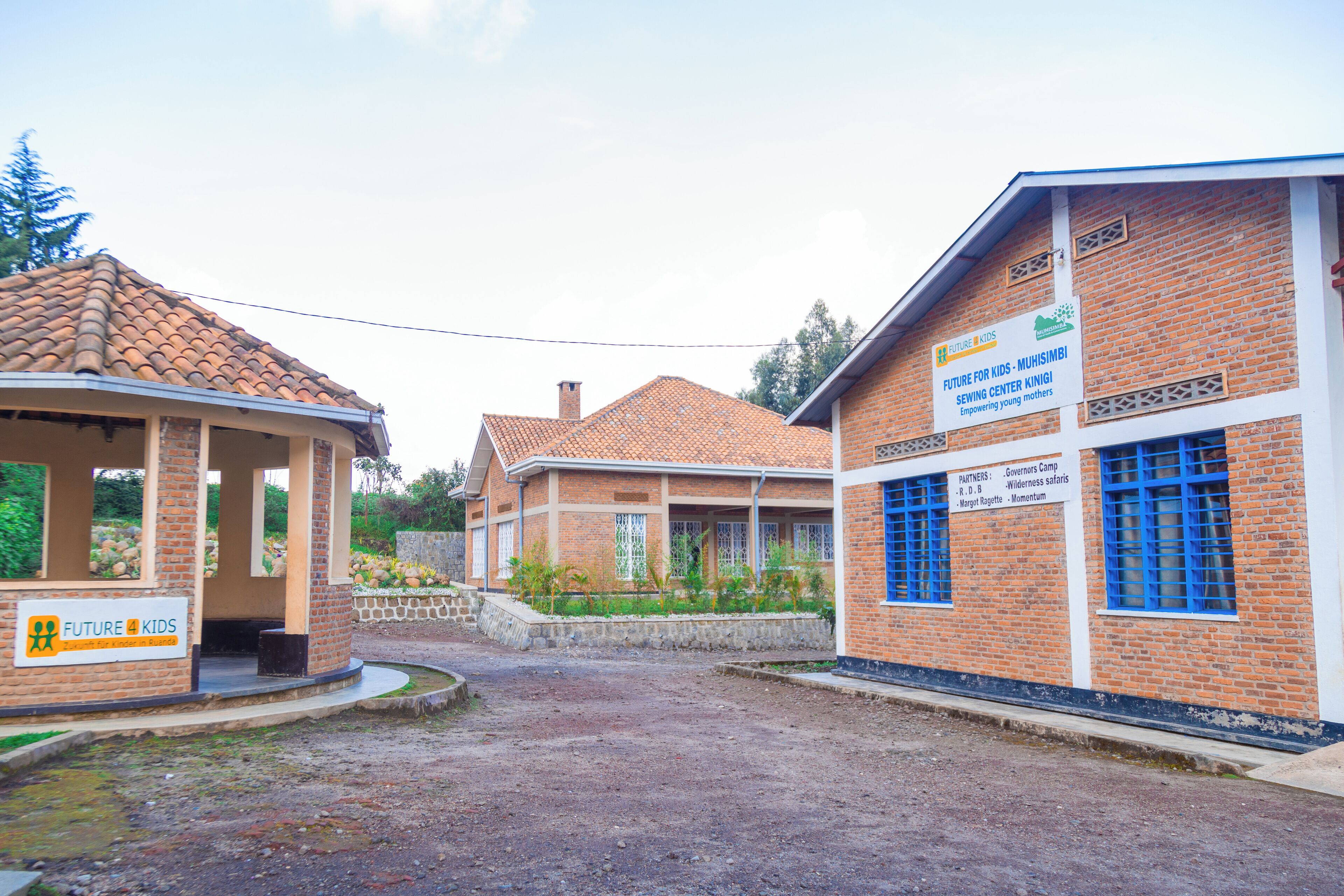A building with a sign for 'Future for Kids - Muhimbili Sewing Center Kingi' and another sign for 'Partners - Governors Camp - Wilderness Safaris - Ngorongoro - Momentum.'