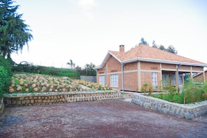 A house with a brick exterior, a tiled roof, and a landscaped garden with a stone wall and plants.