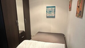 Un dormitorio con una cama, un armario, un espejo y un cartel motivacional en la pared.