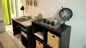 Una habitación con una consola de madera oscura, cestas de mimbre, un reloj y un adorno colgante.
