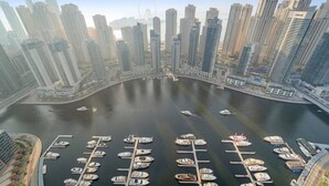A marina with boats docked, surrounded by high-rise buildings and a Ferris wheel in the background. - Dubai Marina 3BR in Vida | Pool, Gym, Balcony, Walk Everywhere (Dubai)