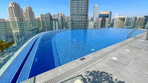 Une piscine à débordement située sur le toit, avec la silhouette de la ville en arrière-plan.