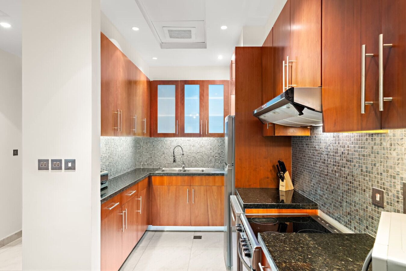 Una cocina moderna con armarios de madera, un lavamanos de acero inoxidable y un salpicadero de azulejos.