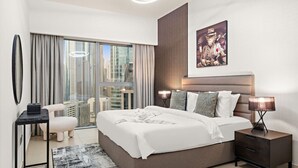 Moderni hotellihuone, jossa on suuri sänky, näköala kaupunkiin, työpöytä ja tuoli.