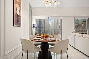 Enjoy meals with a view in this stylish dining area, featuring a round table for four, a fruit bowl, and a chandelier.