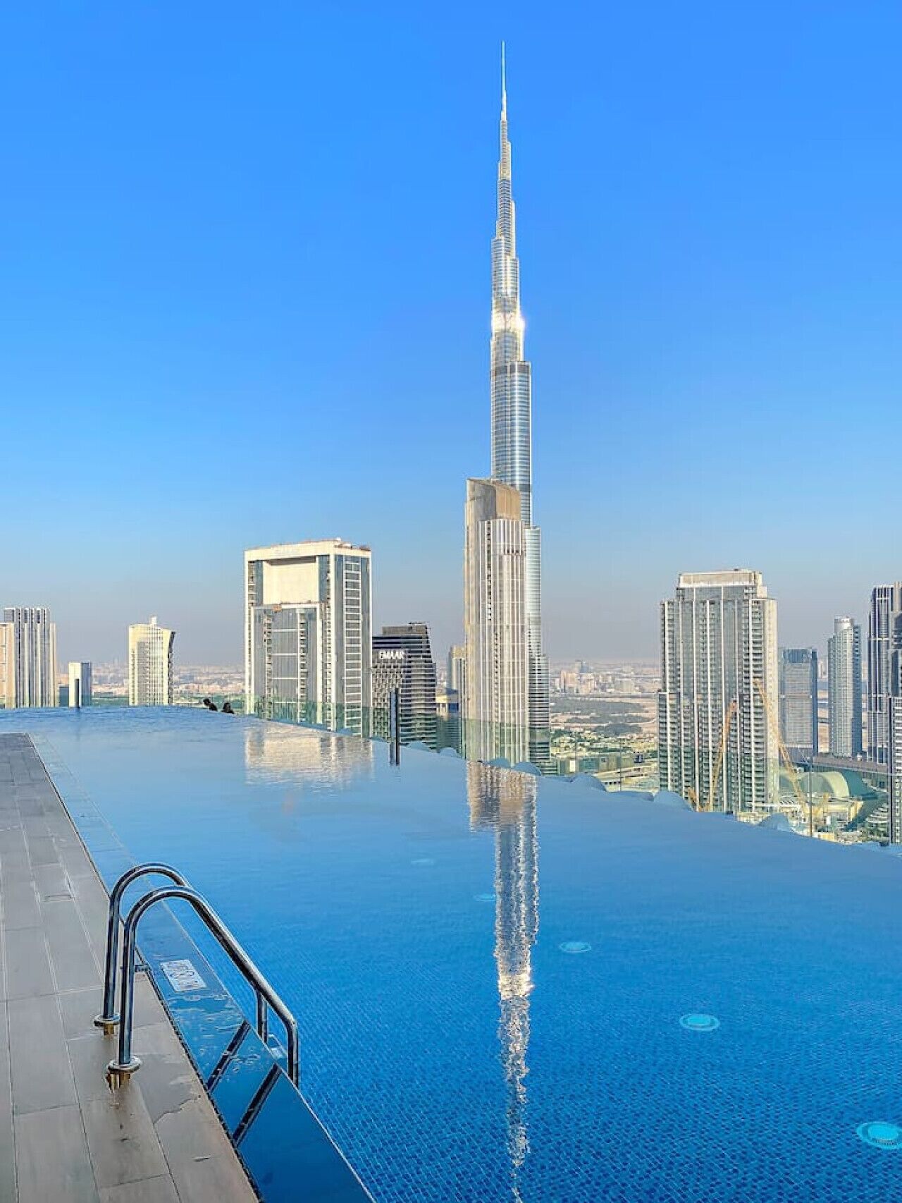 En modern infinitypool med stadens silhuett som bakgrund, inklusive en framträdande skyskrapa.
