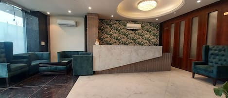 A modern lobby with a reception desk, seating area, and a patterned wall.