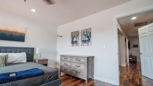 A bedroom with a bed, dresser, and artwork on the wall.