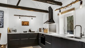 A modern kitchen with dark cabinetry, a large island, and a window providing natural light. - "Thorgot" - 3km from the sea by Interhome (Pandrup)