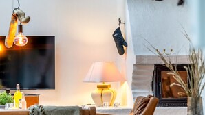 A cozy living room with a leather sofa, a table with a lamp, a fireplace, and a television mounted on the wall. - "Thorgot" - 3km from the sea by Interhome (Pandrup)