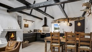A modern kitchen with a fireplace, wooden dining table, and high ceilings with exposed beams. - "Thorgot" - 3km from the sea by Interhome (Pandrup)