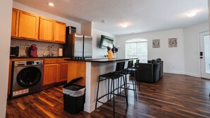 Een moderne keuken met houten kastjes, een roestvrijstalen koelkast en een ingebouwde wasmachine.