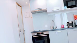 A modern kitchen with a built-in oven, microwave, and a small dining area with a bench.