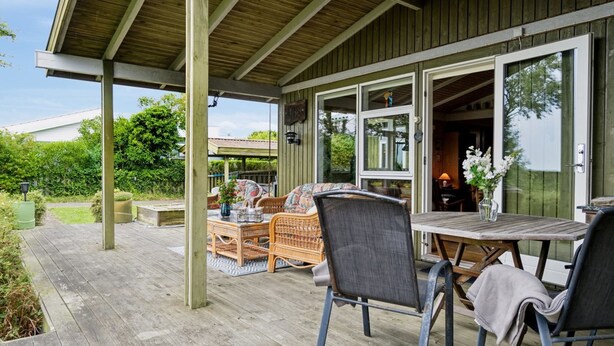 Eine Terrasse im Freien mit Holzdeck, Korbmöbeln und einem Tisch mit Stühlen.