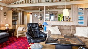 Ein gemütliches Wohnzimmer mit Ledersessel, Teppich mit Muster und Couchtisch mit Fernbedienung.