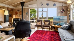 Ein gemütliches Wohnzimmer mit Kamin, Ledersofa und einem großen Fenster mit herrlichem Ausblick.