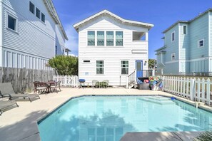 Propiedad residencial con piscina, patio trasero cercado y una casa de dos pisos.