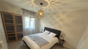 A bedroom with a bed, bedside lamp, and a hanging light fixture. - Villa Moderne Avec Piscine Avignon (Avignon)