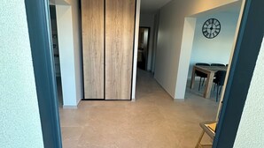 A hallway with a wooden wardrobe, a dining area with a table and chairs, and a wall-mounted clock. - Villa Moderne Avec Piscine Avignon (Avignon)