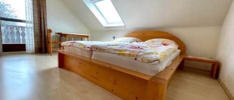 Een slaapkamer met een houten bed, een dakraam en uitzicht op de omgeving.
