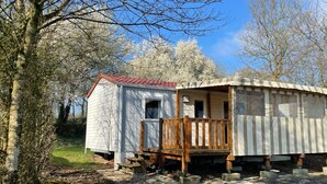 A small, single-story cabin with a porch and a red roof, surrounded by trees. - Mobile home near the Puy du Fou ! (Maulevrier)