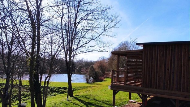 A wooden deck with a view of a lake and trees. - Mobile home near the Puy du Fou ! (Maulevrier)