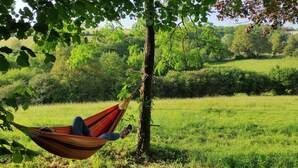 A hammock tied to a tree in a grassy field with a view of a rural landscape. - Mobile home near the Puy du Fou ! (Maulevrier)