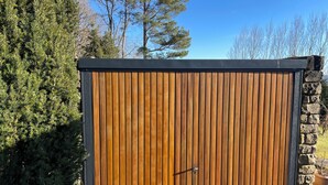 A wooden gate with a metal handle, set against a stone wall and surrounded by greenery.