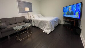 A hotel room with a bed, a sofa, a glass coffee table, a television, and a lamp. - First Class - 2 bedroom house  (Whitby)