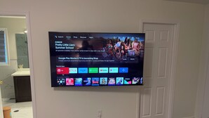 A flat-screen TV mounted on a wall displaying a streaming service interface with various apps and a movie titled 'Pretty Little Liars: Summer School'. - First Class - 2 bedroom house  (Whitby)